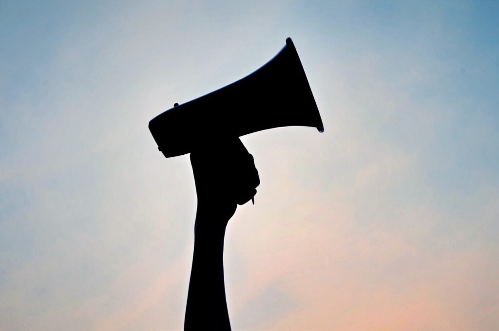 Megaphone silhouette against a pink and blue sky